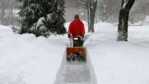 man snow blowing commercial property sidewalk